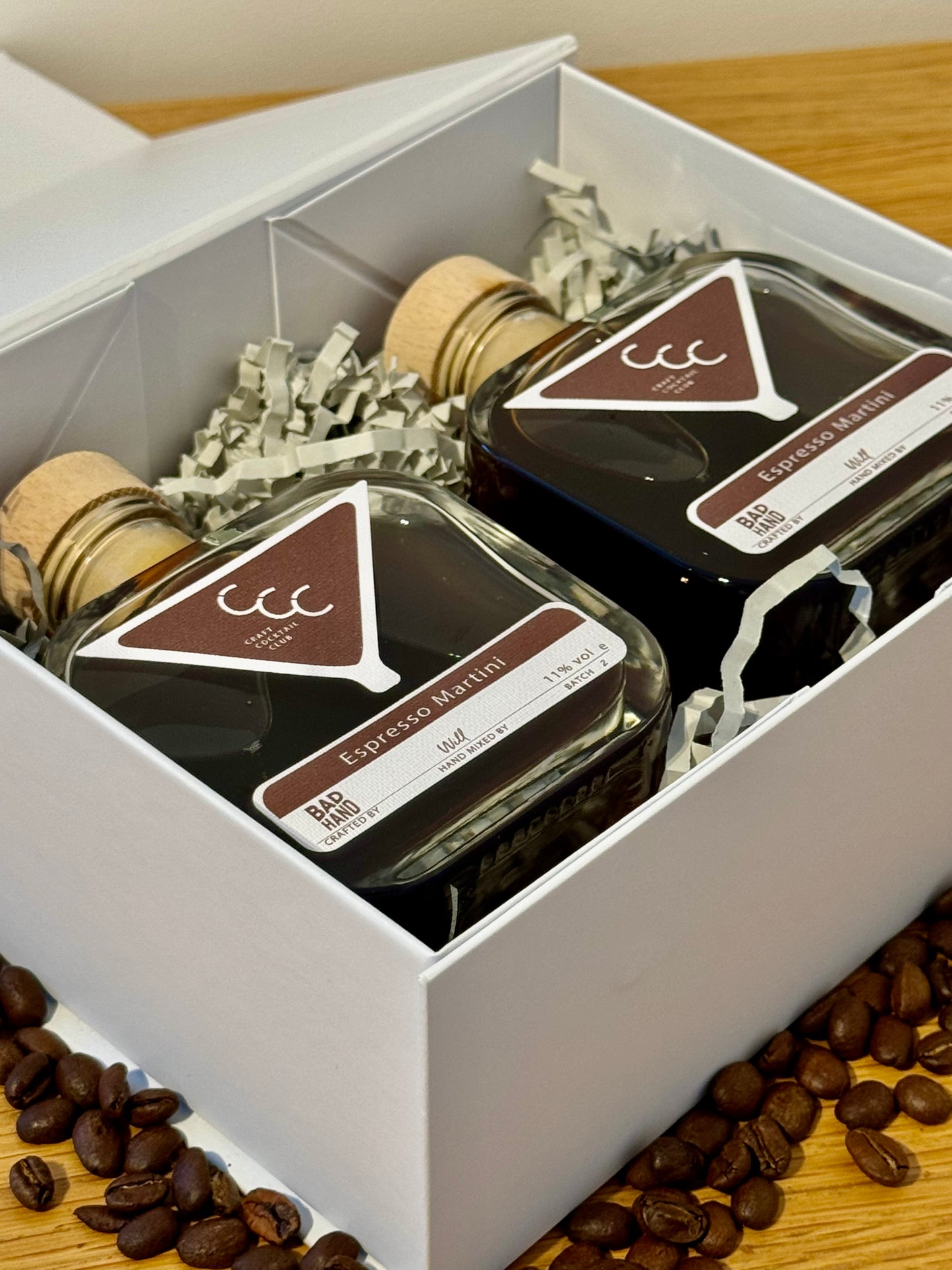 Picture of a gift set of cocktails, with two coffee brown square bottles sat in a gift box on an oak table, label reads craft cocktail club, espresso martini 16% abv