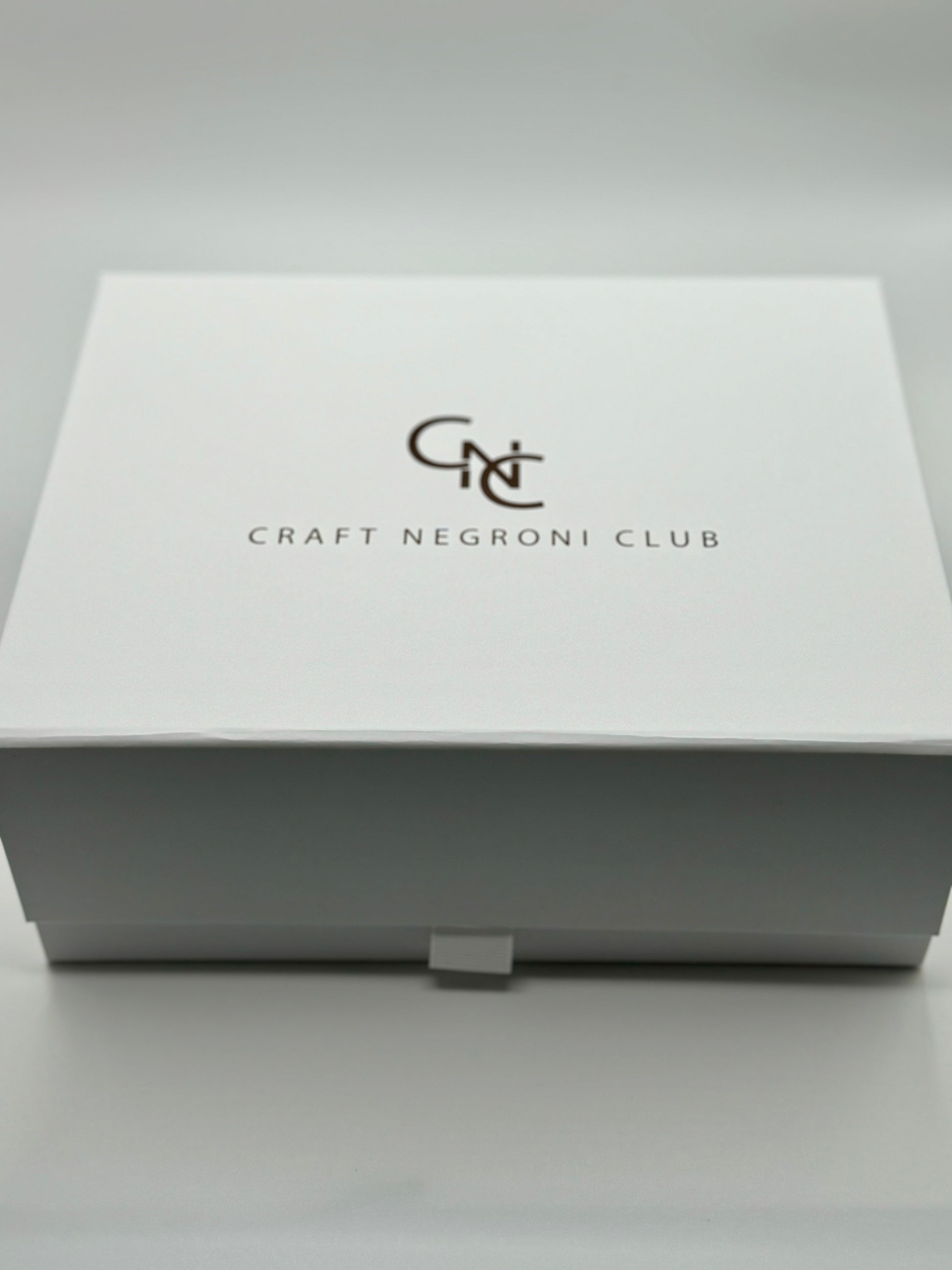 picture of a close white box with metallic bronze writing that reads Craft Negroni Club 