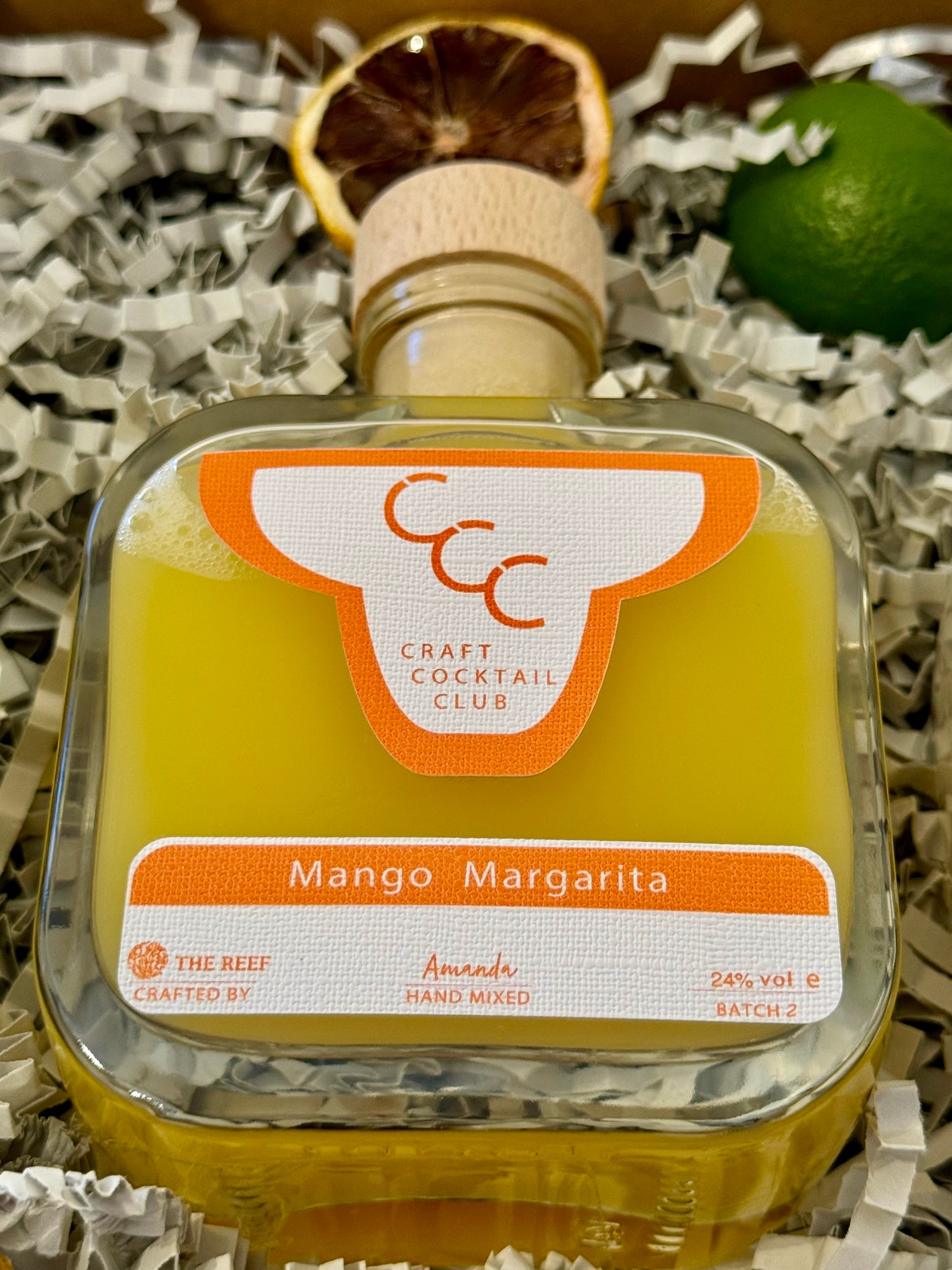 picture of a gift box with a zoomed in look at one orange  bottle that reads Craft Cocktail Club, mango Margarita 