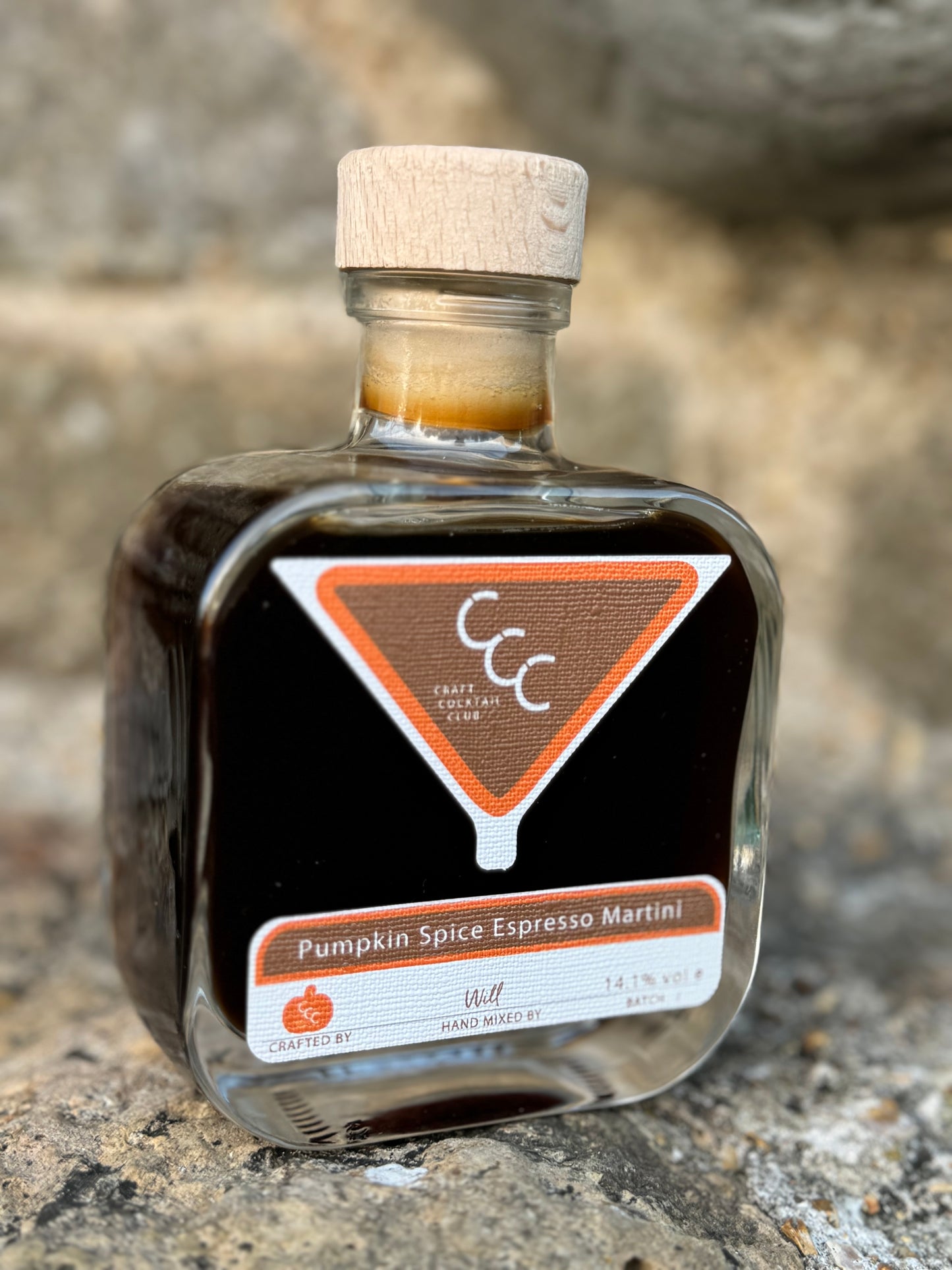 picture of a ready to drink bottle of espresso martini with a label that says craft cocktail club, pumpkin spice. Picture taken on a sandstone rock 