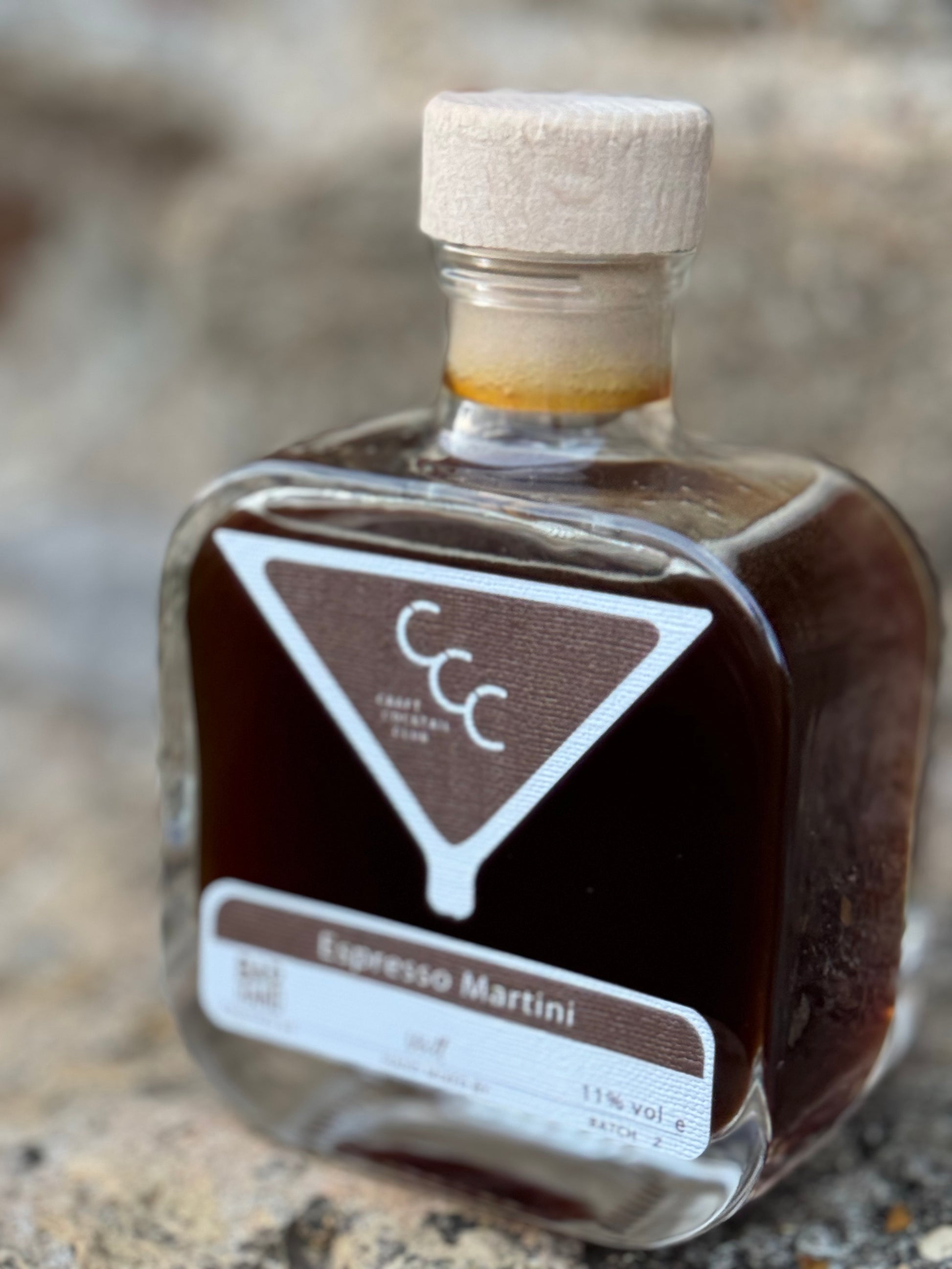 Picture of s single bottle of a craft cocktail club ready to drink cocktail sat on a stone castle, label reads espresso martini 