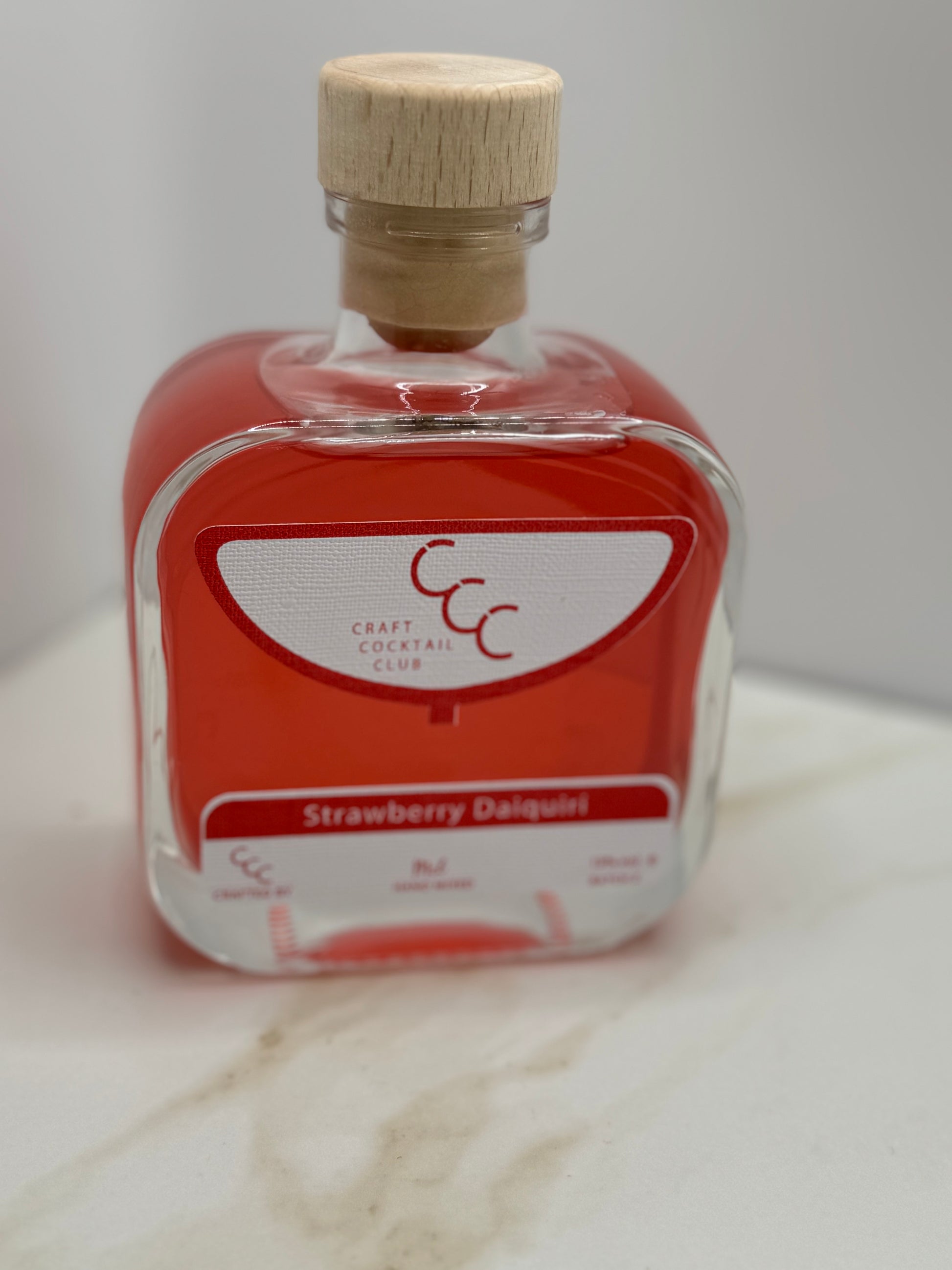 picture of a lone bottle of red liquid in a square glass bottle  containing cocktail 