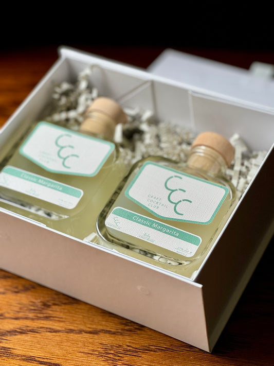 picture of two ready to drink margaritas in a white gift box on a wooden table 