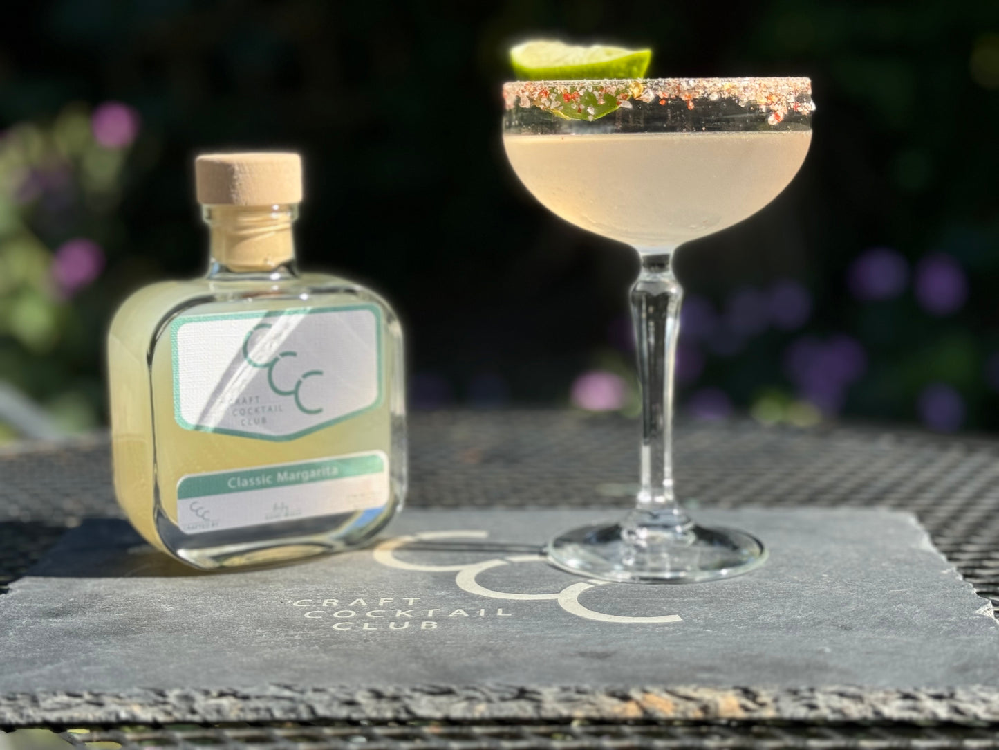 picture of a lime margarita outside on a sunny day with flowers in the background 