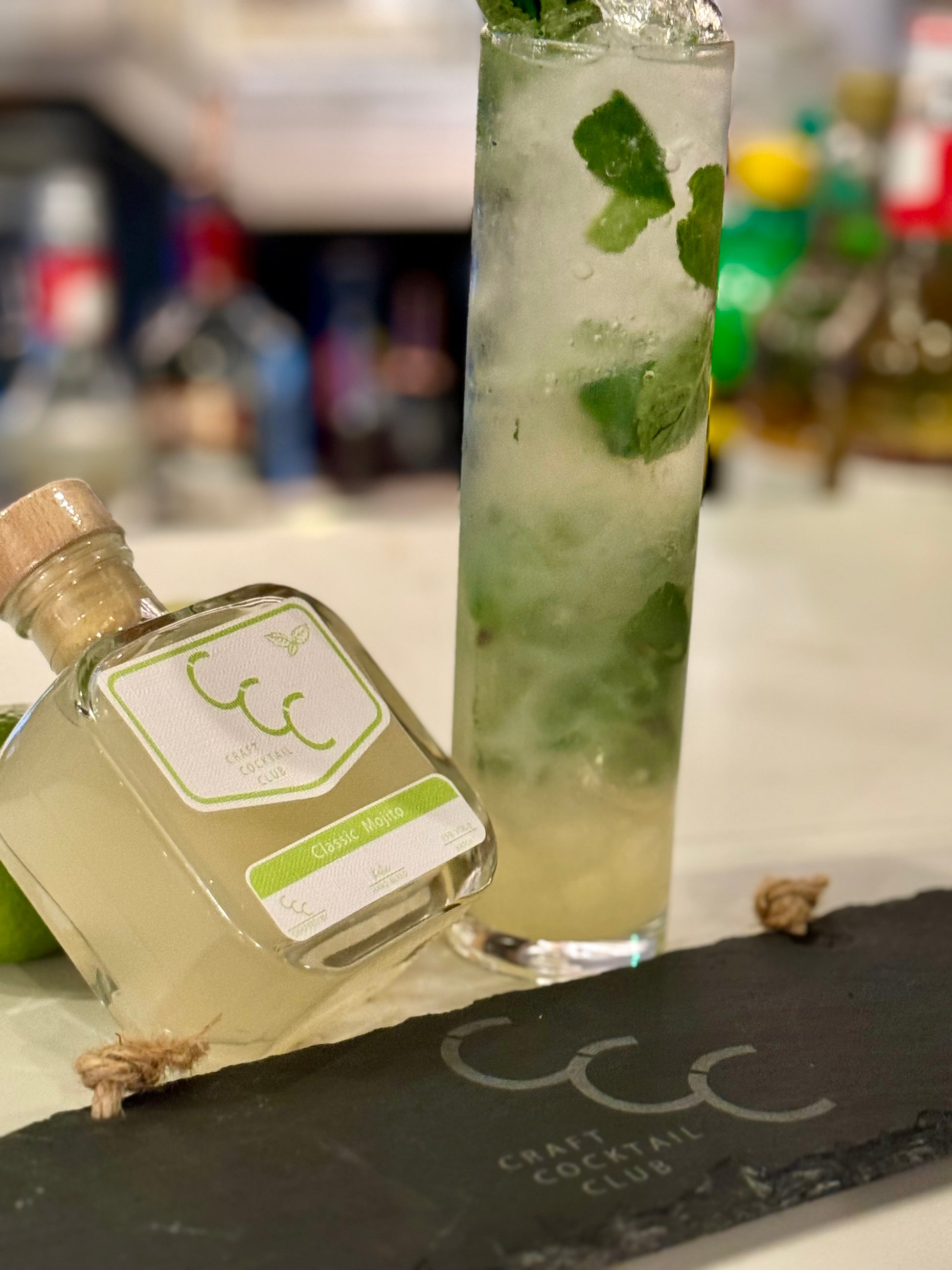 Picture of a mojito Cocktail on a bar next to a bottle of ready to drink mojito that says Craft Cocktail Club 