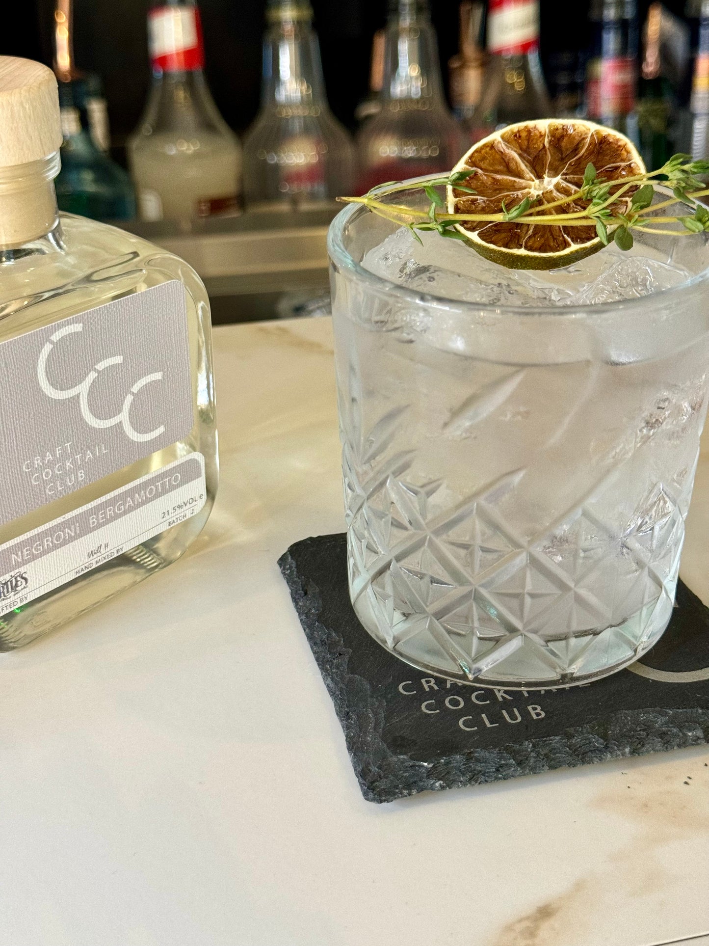 picture of a white negroni on a bar topped with a lime wedge 