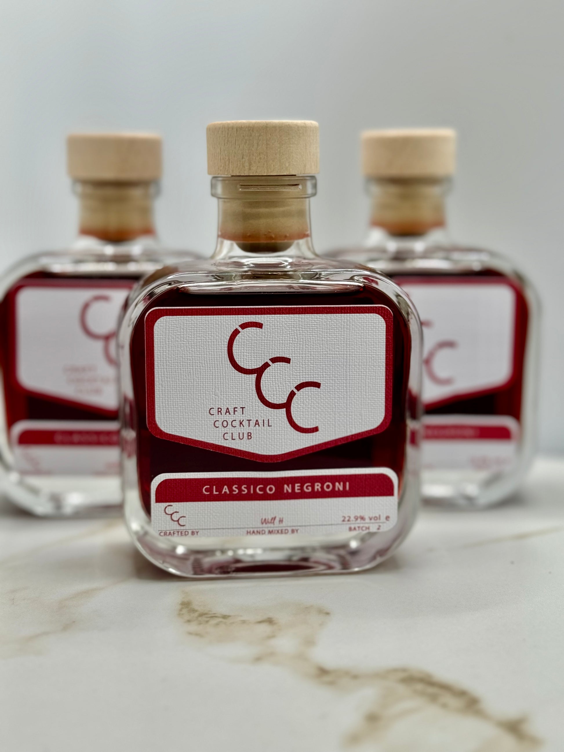 picture  of three Craft Cocktail bottles of negroni on a white tile 