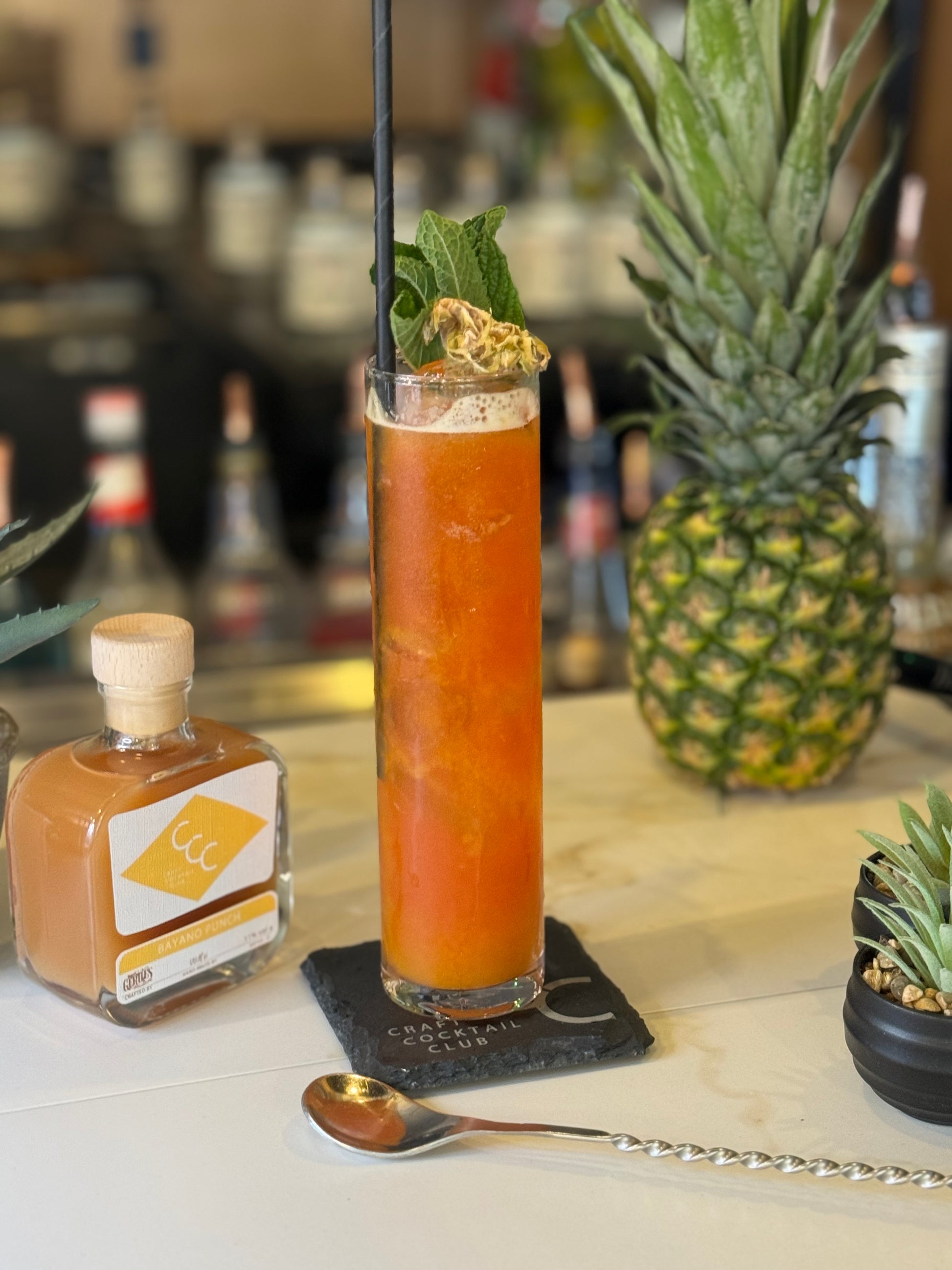 picture of craft cocktail club Bayano Punch next to a pineapple on a bar 