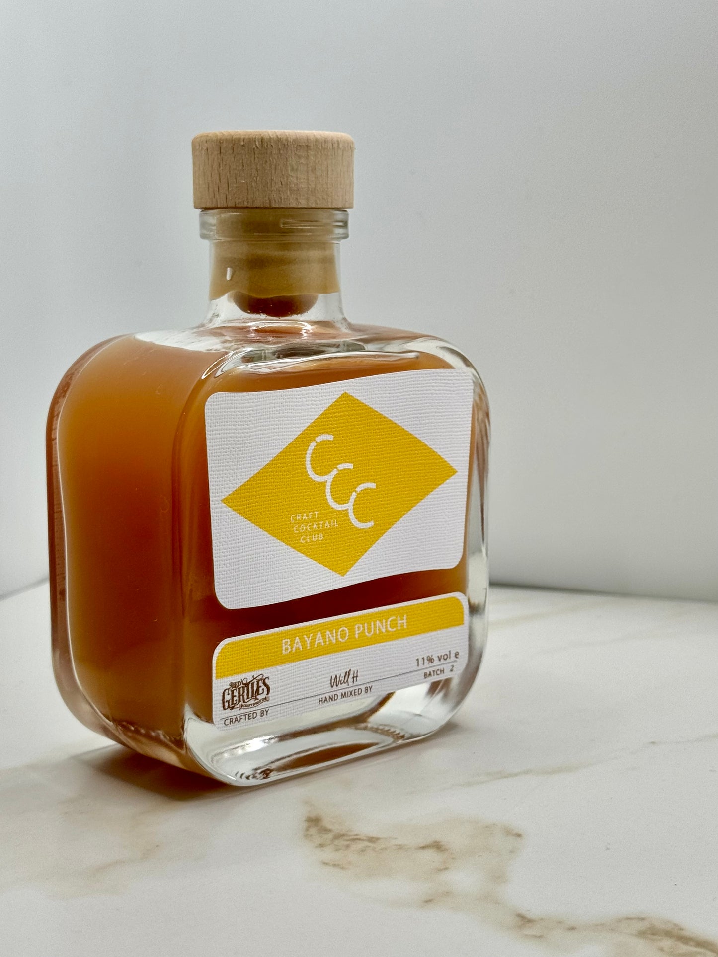 picture of a ready to drink craft cocktail bottle with a yellow label on a cream tile